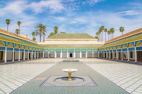 La cour du palais royal de Marrakech, avec des murs bleus et une fontaine centrale.